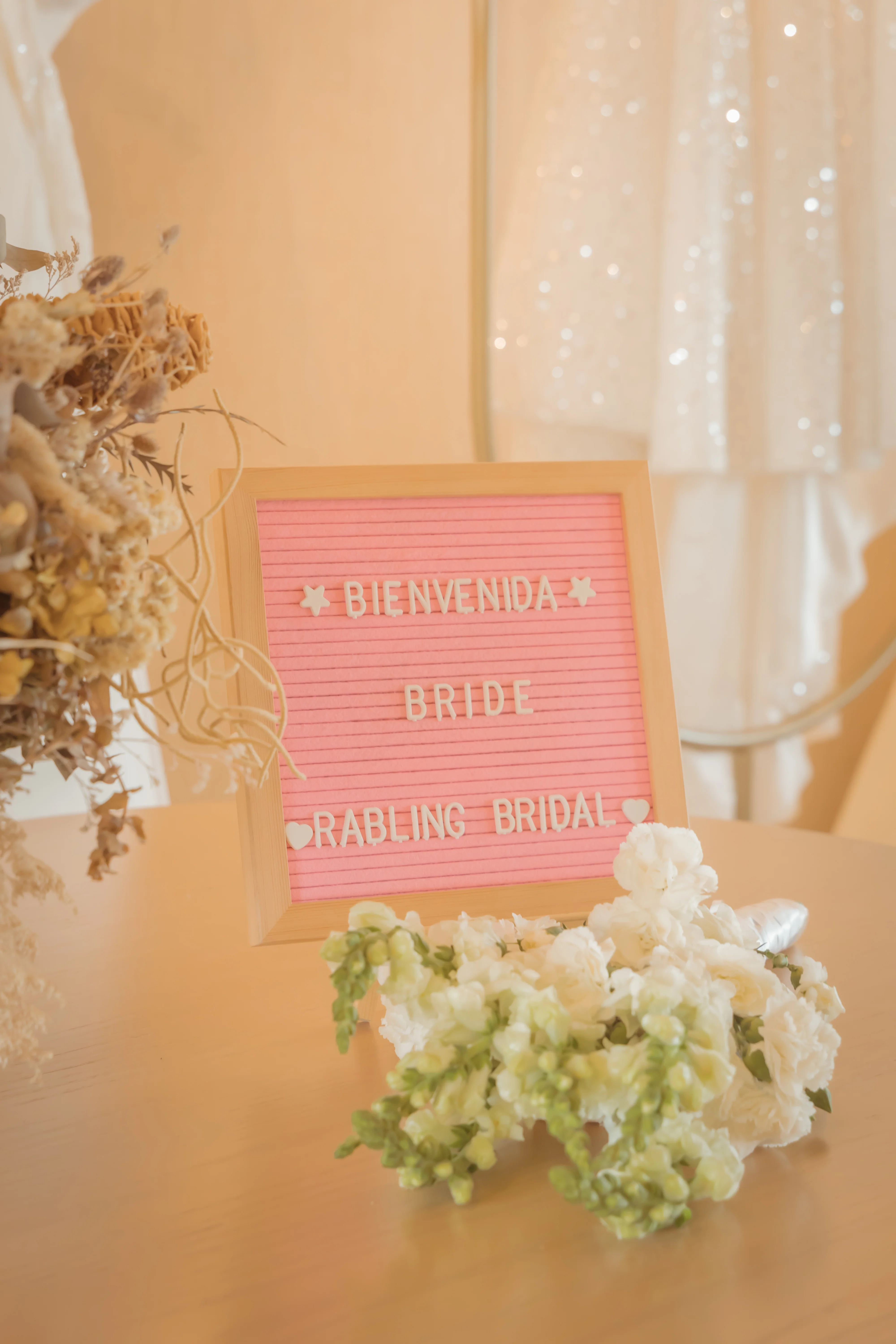 Letrero de bienvenida 'Bienvenida Bride — Rabling Bridal' junto a un arreglo floral, fotografía real de Rabling Bridal